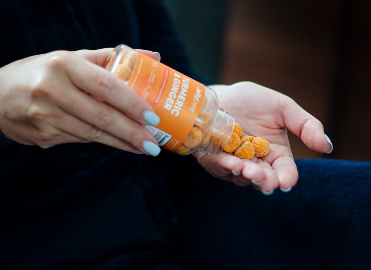 Close-up of a woman holding turmeric ginger gummies in hand, promoting a health supplement.