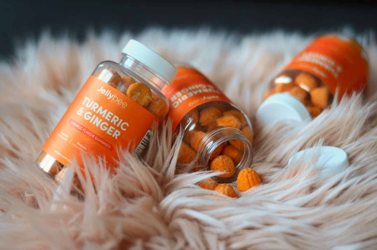 Close-up of turmeric and ginger gummies in jars, emphasizing health benefits on a soft surface.